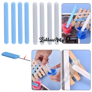 May include: A set of blue and white silicone stirring sticks. The sticks are shown being used to mix resin in clear plastic cups. The image also shows a close-up of a single stick being used to mix resin.