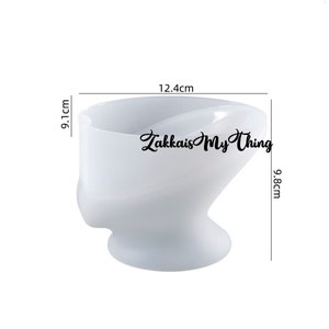 May include: A white, abstract-shaped silicone mold, 12.4 cm wide, 9.1 cm high, and 9.8 cm deep. The mold has a rounded base and a wide opening. The text "Zakkais My Thing" is printed on the side.