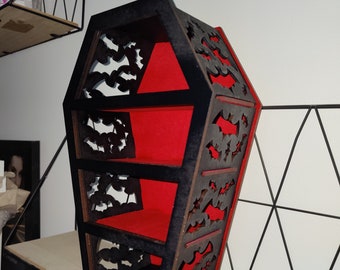 Op de afbeelding: Een zwarte houten kistvormige plank met drie planken. De planken zijn bekleed met rood vilt en de voorkant van de plank is versierd met een uitgesneden ontwerp van vleermuizen.