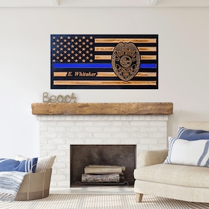 May include: Wooden American flag with a blue line and a police badge with the text "Patrolman Fort Myers Police 530" and the name "E. Whitaker" below the blue line.