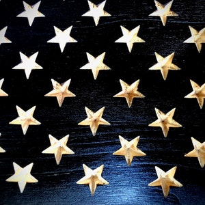 May include: A close-up of a black wooden surface with a pattern of gold stars. The stars are arranged in rows and columns, creating a repeating pattern.