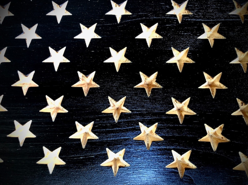 May include: A close-up of a black wooden surface with a pattern of gold stars. The stars are arranged in rows and columns, creating a repeating pattern.