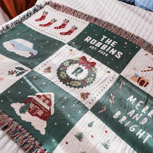 May include: A woven Christmas blanket with a patchwork design. The blanket features green and white squares with festive images like stockings, a wreath, and a house. The text "THE ROBBINS EST. 2024" and "MERRY AND BRIGHT" are also displayed.