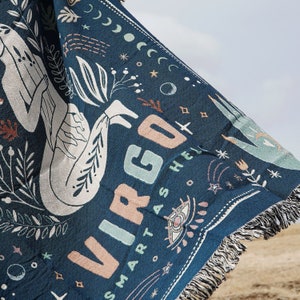 May include: A blue woven throw blanket with a white and pink illustration of a Virgo zodiac sign and the text "SMART AS HELL".