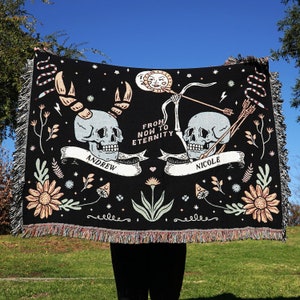 May include: Black woven throw blanket with a skull and crossbones design. The blanket features the text "From Now to Eternity" and the names "Andrew" and "Nicole".