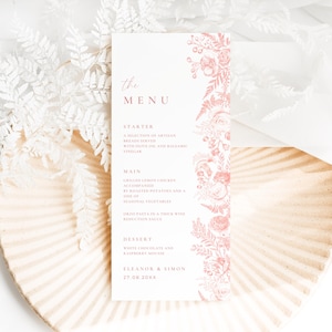 May include: A vertical white menu card featuring the text THE MENU, STARTER, MAIN, DESSERT, ELEANOR & SIMON, and 27.09.20XX. The right side is decorated with a detailed pink floral and botanical illustration of roses, berries, and fern leaves.
