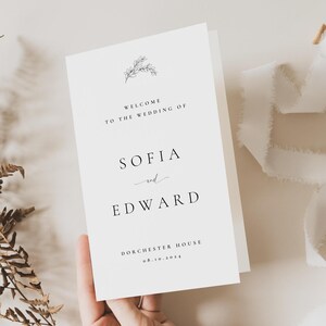 May include: A white wedding invitation card with black text. The card reads "WELCOME TO THE WEDDING OF SOFIA and EDWARD" with the date 08.10.2024 and "DORCHESTER HOUSE" at the bottom. A delicate floral illustration is at the top.