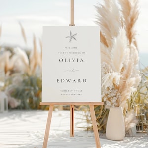 May include: A white wedding welcome sign with a starfish illustration at the top. The sign reads "Welcome to the wedding of Olivia and Edward, Somerly House, August 27th 20XX".