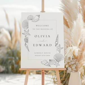 Könnte beinhalten: Ein weißes Hochzeitsschild mit schwarzem Text und Illustrationen von Muscheln. Das Schild lautet "Willkommen zur Hochzeit von Olivia und Edward, Somerly House, 27. August 20XX".