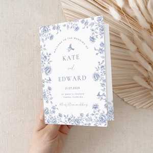 May include: A white wedding invitation with a blue floral border. The text reads "Welcome to the wedding of Kate and Edward 21.07.202X St Mary's Church Tampa, Florida #thewilliamwedding"