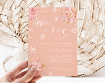 Puede incluir: Una invitación de ducha nupcial rosa con un diseño floral de acuarela y copos de nieve. El texto dice "Snow in Love" e incluye el nombre de la novia, la fecha y la ubicación de la ducha.