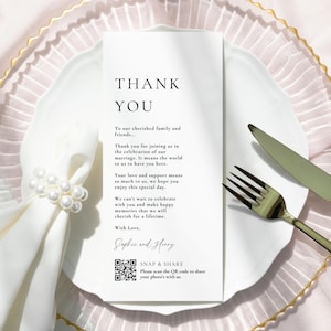 May include: A white folded card with the words "THANK YOU" in a minimalist font. The card is on a white plate with a napkin ring and silverware. The card includes a thank you message and a QR code.
