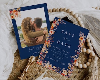 May include: Save the date card with a floral design in shades of orange, red, and yellow on a navy blue background. The card features a photo of a couple kissing and the text "Save the Date" with the names Sophie and Henry and the date August 27th, 2023.