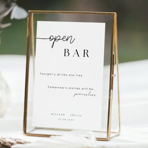 Può includere: Un cartello con cornice dorata con le parole "open BAR" in corsivo nero. Il cartello include il testo "Tonight's drinks are free" e "Tomorrow's stories will be... priceless." Sono visualizzati anche i nomi "WILLIAM AMELIA" e la data "27.08.20XX".