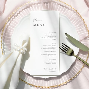 Peut inclure: Une carte de menu blanche avec une bordure dorée, avec une police d'écriture manuscrite simple. Le menu comprend une entrée, un plat principal et un dessert. Le texte indique "the MENU", "STARTER", "MAIN", "DESSERT", "Olina & Edvard", et "27.08.20XX".