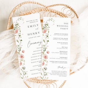 May include: Two wedding ceremony programs with floral and greenery designs. The programs display the names "Emily and Henry" and "The Wedding Party." The programs are on a woven basket.