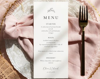 May include: A wedding menu card with a floral design at the top, listing a meal's courses. The menu includes a starter, main course, and dessert. The card is on a decorative plate with a pink napkin and gold fork.