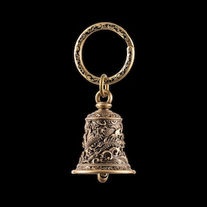 May include: A detailed brass bell keychain with a dragon motif. The bell is suspended from a decorative ring. The bell's surface features intricate carvings of dragons and waves, with a dark background.