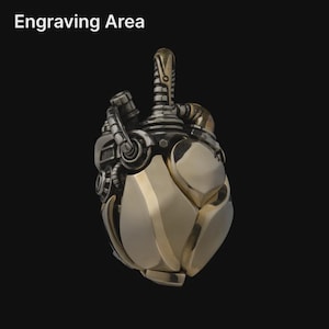 May include: A metallic pendant shaped like an anatomical heart with mechanical details, including pipes and valves. The surface features a smooth, polished gold-tone finish with dark, oxidized silver-tone accents. The text Engraving Area is visible.