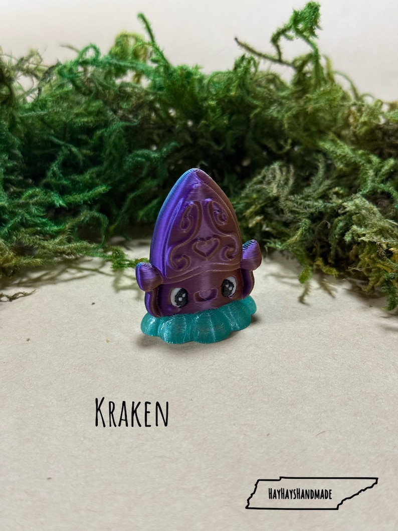 May include: A 3D-printed Kraken figurine in purple and teal, with a decorative design on its head and a frilly base. The word "KRAKEN" is printed below the figurine. The HayHaysHandmade logo is at the bottom.