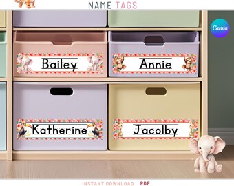 Könnte beinhalten: Rosa Dschungel-Themen-Namensschilder für Aufbewahrungsboxen. Die Schilder haben ein rosafarbenes Blumenmuster mit Dschungeltieren wie Elefanten, Tigern und Tukanen. Die Namen "Bailey", "Annie", "Katherine" und "Jacob" sind auf den Schildern gedruckt.