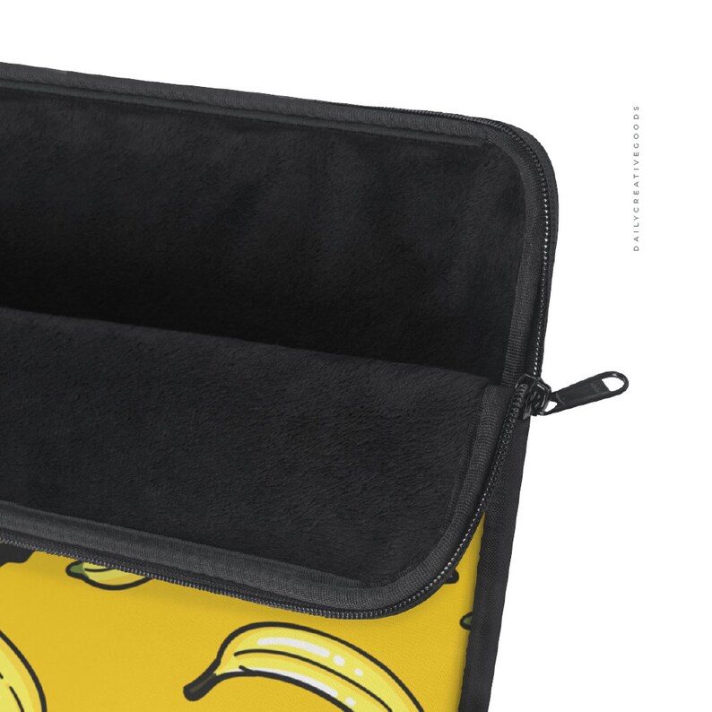 May include: A black laptop sleeve with a zipper closure. The sleeve has a yellow background with a repeating pattern of yellow bananas. The inside of the sleeve is lined with black fleece.