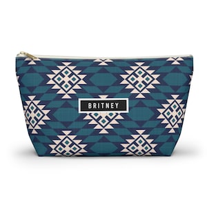 May include: A white ceramic mug with a black handle and the text "But First, Coffee" in a bold, black font. The mug is set against a blurred background, suggesting a cozy setting. The mug appears to be approximately 4 inches tall.