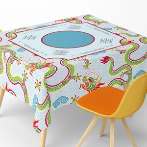 May include: A light blue tablecloth with a repeating pattern of green and red dragons. The tablecloth has a central light blue area with a red border and text. The background features a wave pattern. A yellow chair with an orange seat is in the foreground.