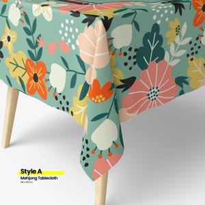 May include: A floral tablecloth with a teal background and a pattern of large flowers in shades of orange, pink, yellow, and white. The tablecloth is on a wooden table. The text "Style A Mahjong Tablecloth 140 x 140 cm" is visible.