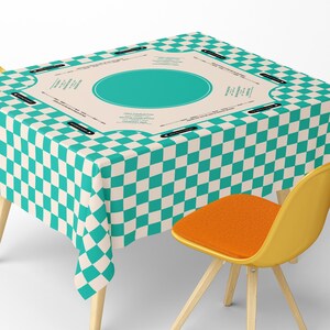 May include: A square tablecloth with a teal and white checkered pattern. The center features a teal oval shape and text. A yellow chair with an orange seat is partially visible.