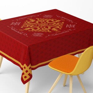 May include: A red tablecloth with a gold dragon design and text. The tablecloth has a repeating pattern and gold trim. A yellow chair with an orange seat is in the foreground.