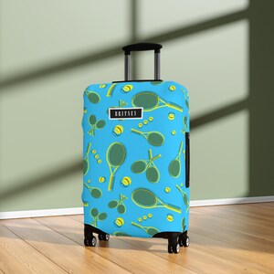 May include: A blue suitcase cover with a tennis racket and ball pattern. The suitcase cover has the name "BRITNEY" printed on it.