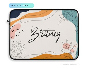 May include: A laptop sleeve with an abstract design in shades of orange, blue, and pink. The sleeve has a white background with the name "Britney" written in black cursive. The sleeve is made of a soft, durable material and is perfect for protecting your laptop.