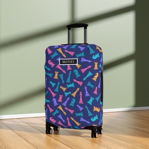 May include: A blue suitcase with a chess piece pattern. The suitcase has a black handle and wheels. The text "BRITNEY" is printed on the suitcase.
