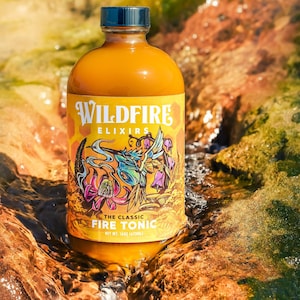 May include: A bottle of Wildfire Elixirs Fire Tonic, 16 fl oz (473ml), with a colorful label featuring floral and insect illustrations. The bottle has a dark blue cap and is set in a natural, flowing water environment.