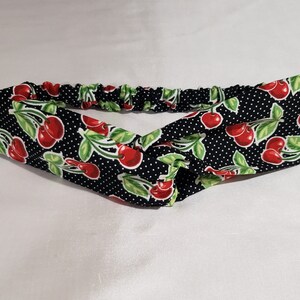 May include: A black headband with a white polka dot pattern and a red cherry print. The headband is made of a soft, stretchy fabric and is perfect for keeping hair out of your face.