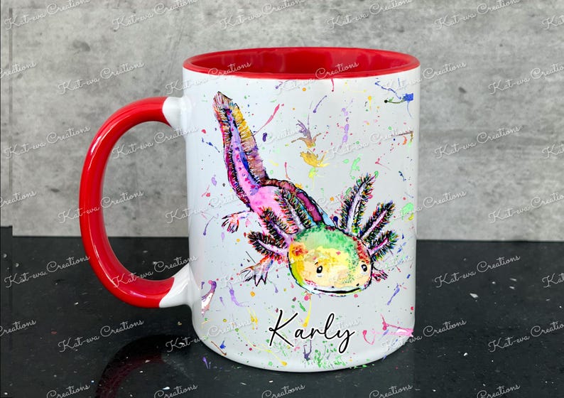 Pu&ograve; includere: Una tazza in ceramica bianca con un bordo e un manico rossi. La tazza presenta un'illustrazione ad acquerello colorata di un axolotl con il nome "Karly" scritto sotto.