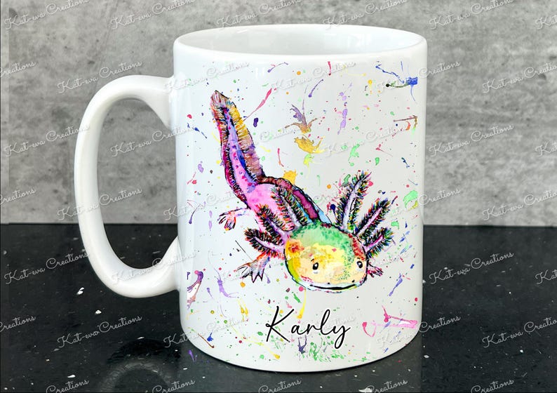 Pu&ograve; includere: Una tazza in ceramica bianca con un'illustrazione ad acquerello colorata di un axolotl. L'axolotl &egrave; rosa, verde e giallo con un contorno nero. Lo sfondo &egrave; bianco con schizzi di vernice colorata. La tazza ha un manico nero e il nome "Karly" &egrave; scritto in nero sotto l'axolotl.