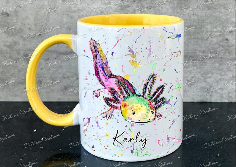 Pu&ograve; includere: Una tazza in ceramica bianca con un bordo e un manico gialli. La tazza presenta un'illustrazione ad acquerello colorata di un axolotl con il nome "Karly" scritto sotto.