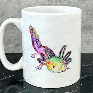 Pu&ograve; includere: Tazza in ceramica bianca con un'illustrazione colorata di un axolotl. L'axolotl &egrave; rosa, verde e giallo con branchie piumate.