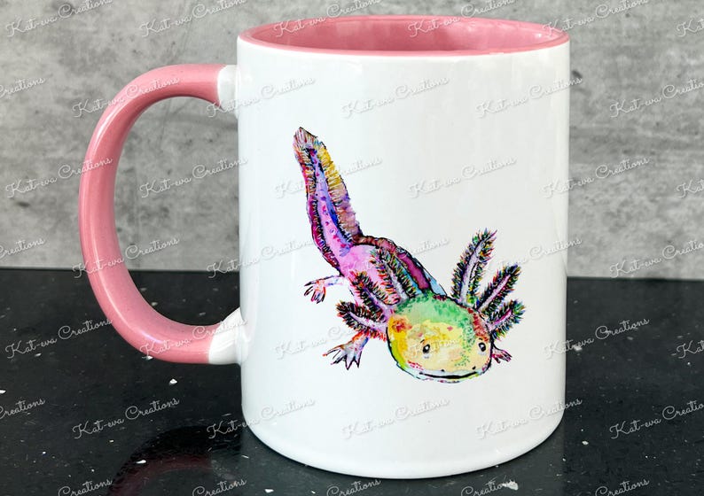 Pu&ograve; includere: Una tazza in ceramica bianca con un manico e un bordo rosa. La tazza presenta un'illustrazione colorata di un axolotl, un tipo di salamandra, con colori rosa, verde, giallo e blu.