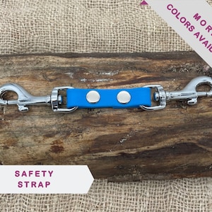 May include: A blue leather safety strap with two silver swivel clips and two silver metal accents.  The strap says "SAFETY STRAP" on a white label.