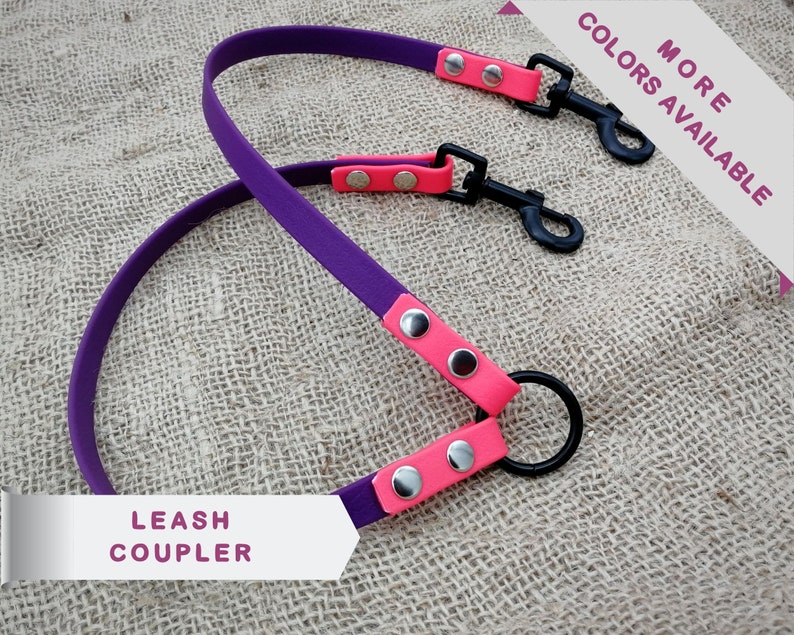 May include: A purple and pink leash coupler with black metal clasps and a black metal ring. The leash coupler has the text "LEASH COUPLER" and "MORE COLORS AVAILABLE".
