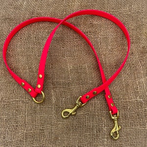 May include: A bright pink dog lead with two gold metal clips. The lead is made of a durable material and is perfect for walking your dog.