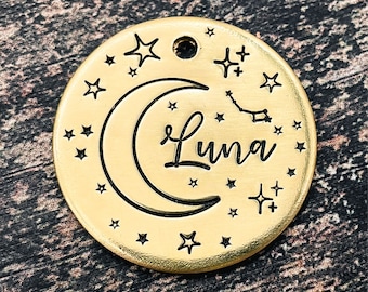 May include: Gold-toned metal pet tag with a crescent moon and stars design. The tag is engraved with the name "Luna".