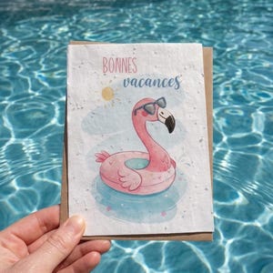 Peut inclure: Une carte de vœux rectangulaire à la surface blanche texturée illustrée d'un flamant rose portant des lunettes de soleil noires dans une bouée gonflable rose. Le texte Bonnes vacances est écrit en lettres cursives roses et bleues.