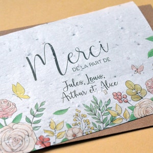 May include: A white card with a brown border and a floral design. The card has the text 'Merci de la part de Jules, Louis, Arthur et Alice'.