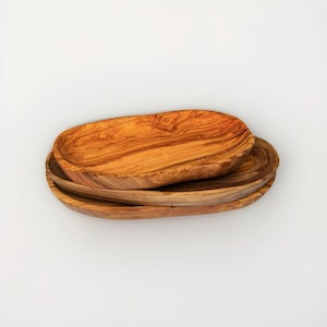 May include: A handmade, wooden cutting board with a natural finish. The board features a live edge on one side and a rectangular shape. It is approximately 18 inches long and 12 inches wide.