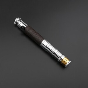 May include: A silver and brown lightsaber with a gold accent at the end. The lightsaber has a textured brown grip.