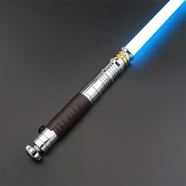 May include: A silver and brown lightsaber with a blue blade. The lightsaber has a leather-wrapped handle and a gold accent.